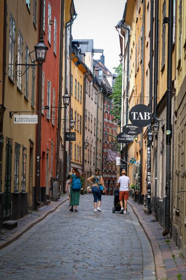 En smal gatan med färgglada byggnader och människor som promenerar.